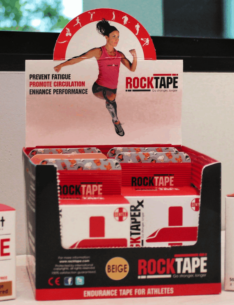 Display box of RockTape Sensitive kinesiology tape in beige, featuring promotional text “Prevent Fatigue, Promote Circulation, Enhance Performance” with an athletic female figure on the packaging.