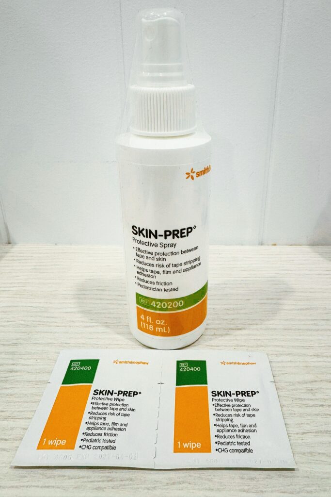 Skin-Prep protective spray bottle and wipes by Smith & Nephew, used to create a barrier on the skin before applying medical or kinesiology tape